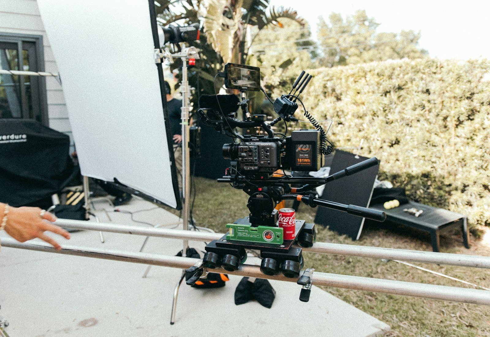 Outdoor location shoot showing dolly tracks, lighting, and grip equipment from multiple production vendors